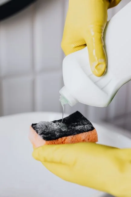 Un travailleur nettoyant les vitres d’un gratte-ciel avec un harnais dans un environnement urbain.